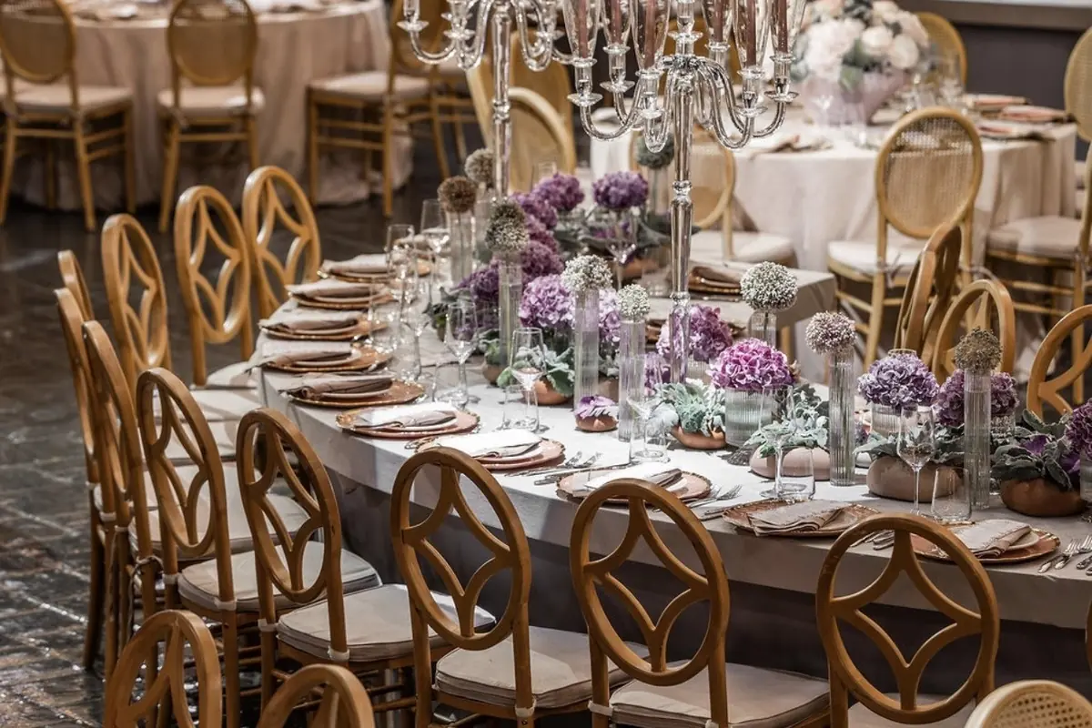 Tables rondes et chaises dorées sous les chandeliers